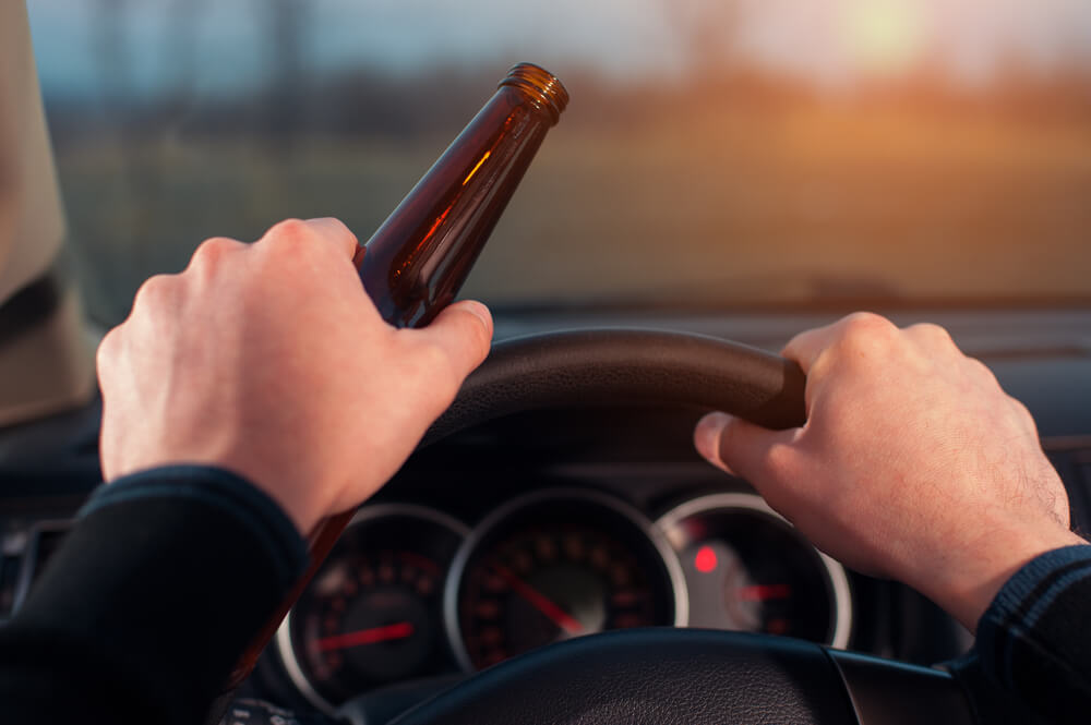 Drunk driver with beer bottle in car.