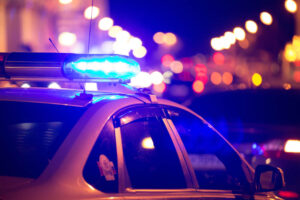 Blue light flasher atop of a police car. City lights on the background. Blue light flasher atop of a police car. City lights on the background.