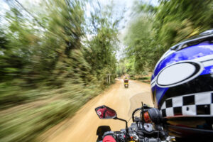 Man is riding a motorcycle at high speed on a dirt road